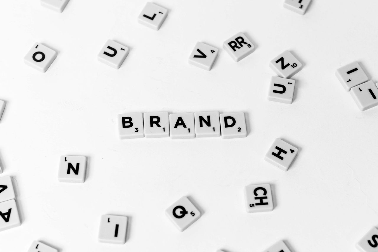 gallery-3 A flat lay of scattered letter tiles forming the word 'BRAND' on a white background.
